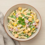 Kids Pasta Salad in a rustic bowl with peas, corn, ham, and cheese