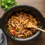 Crockpot Santa Fe Chicken recipe in a slow cooker with shredded chicken, corn, beans, and tomatoes.