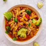 Bowl of Slow Cooker Chicken Tortilla Soup topped with avocado and tortilla strips